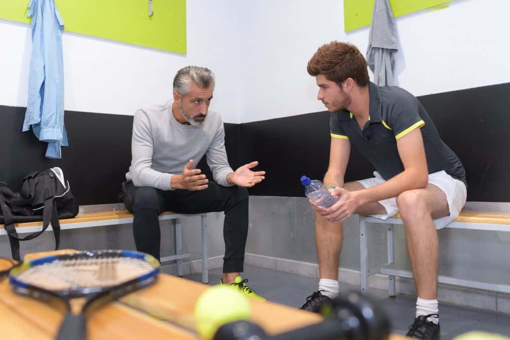 coach talking to tenis player in locker room